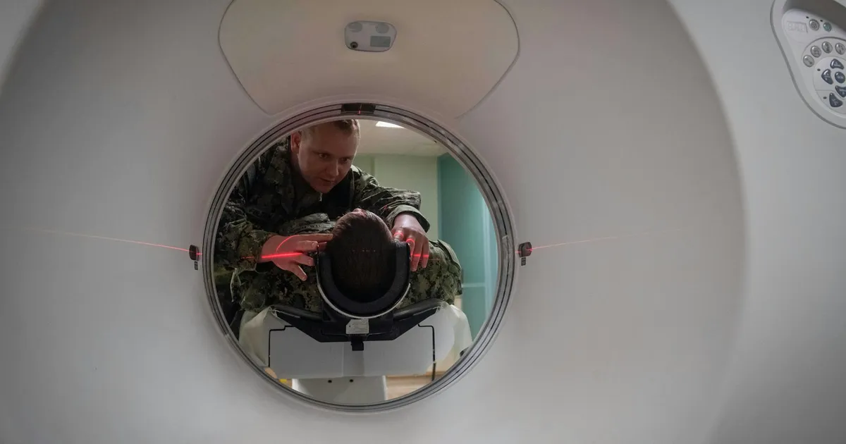 Técnico colocando a un paciente en el TAC antes de la prueba