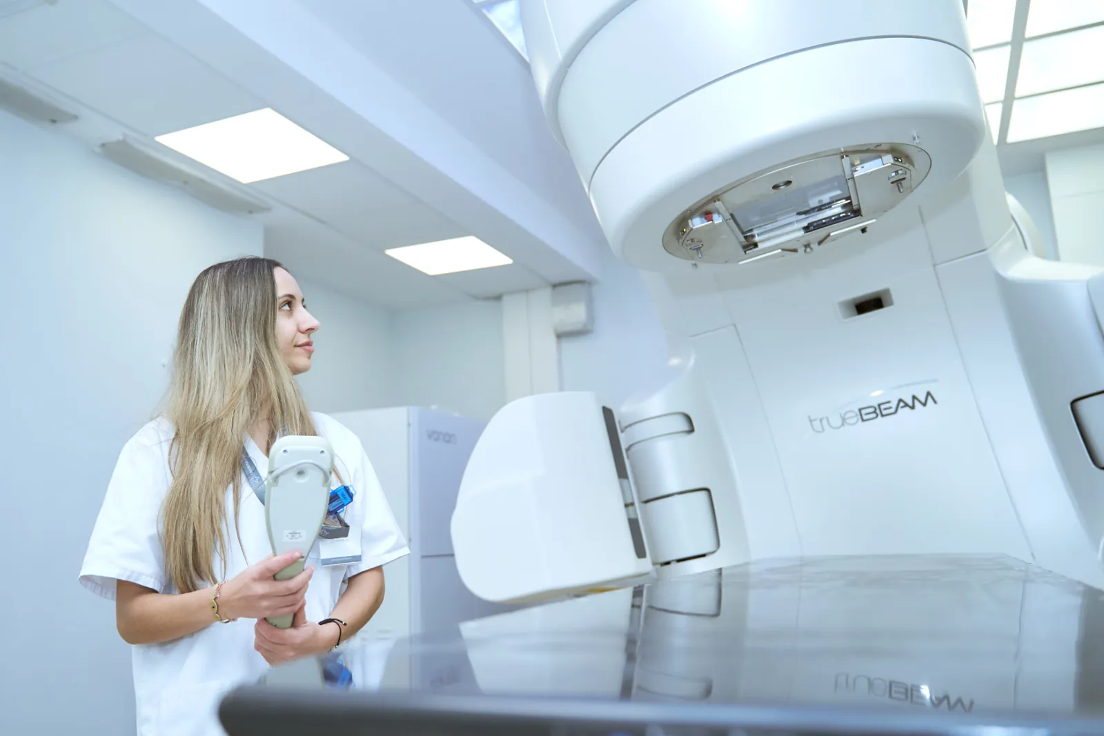 Alumna de Sanitio junto a un acelerador TrueBeam